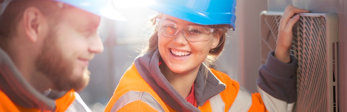 En kvinnlig och en manlig elinstallatör installerar en luftvärmepump.