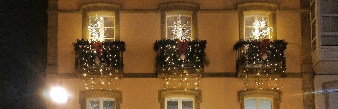 Hus med flera balkonger dekorerade med ljusslingor.