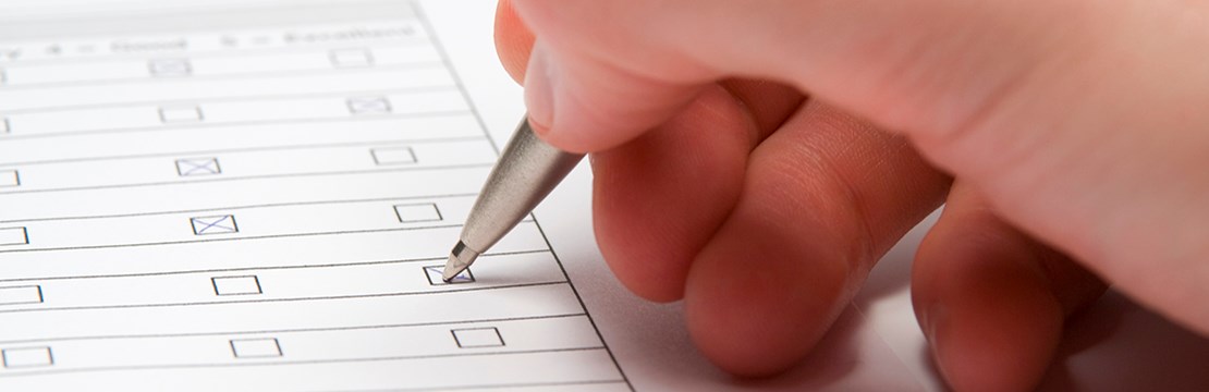 Hand fyller i ett pappersformulär med bläckpenna.