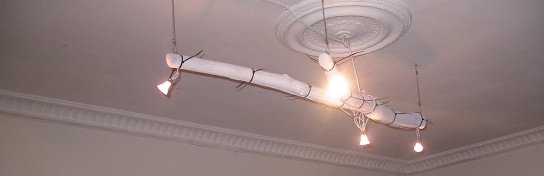 Egentillverkad lampa hänger från dekorerat tak.