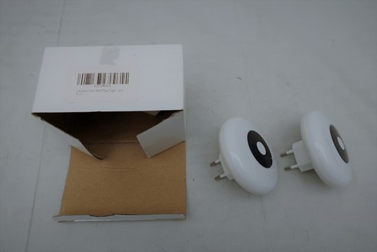 Två vita nattlampor i plast och en vit förpackning med en sträckkod